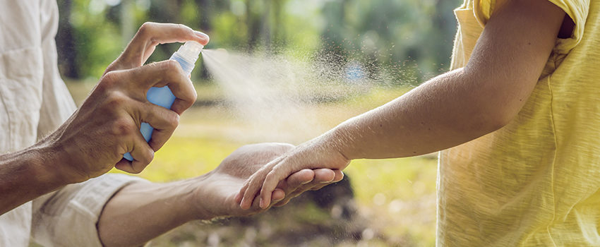 dad and son use mosquito spray.Spraying insect repellent on skin outdoor