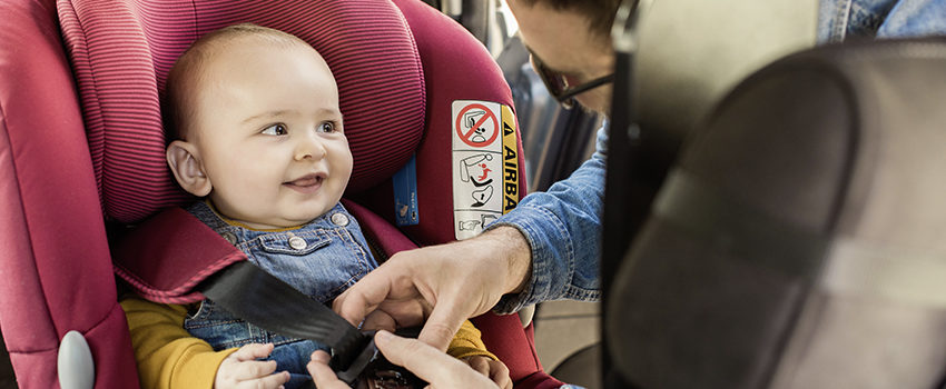 Father fasten his baby in car seat