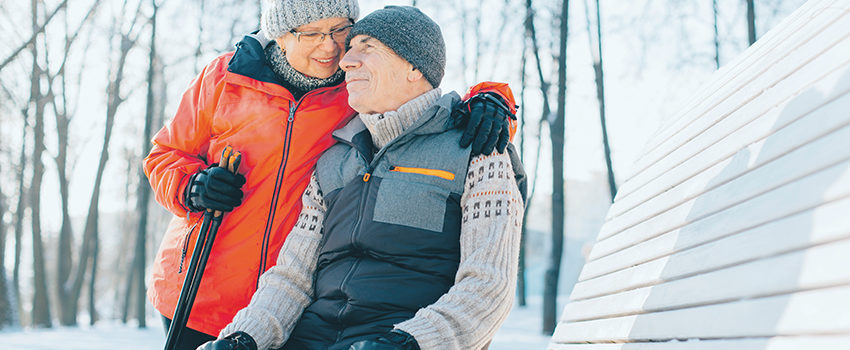 Pretty senior couple sitting with nordic walking poles in winter