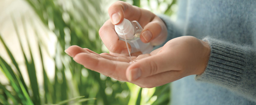 Woman using antibacterial hand sanitizer, closeup