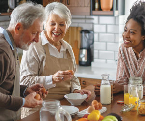 Black woman together with caucasian grandparents in kitchen