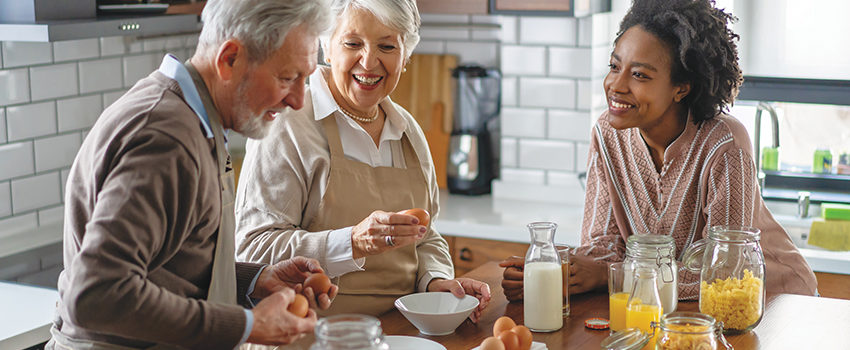 Black woman together with caucasian grandparents in kitchen