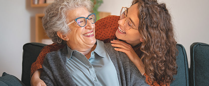 Grandmother and granddaughter laughing and embracing at home