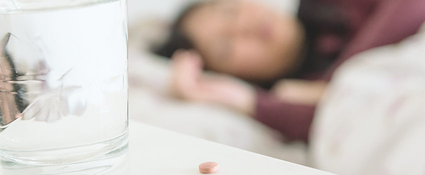 Médicament avec un verre d'eau et une femme dormant en arrière