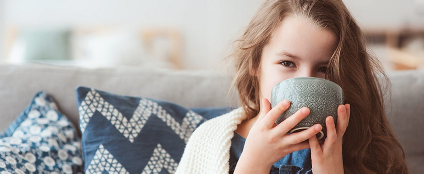 child girl drinking hot tea to recover from flu. Healing kids and protect immunity from seasonal virus, health concept