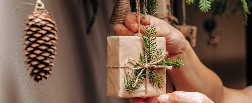 Christmas decor on the wall.Fir branches decorated with gift boxes in craft paper and fir cones.Eco-friendly concept.New Year and Christmas concept.Selective focis,close up.