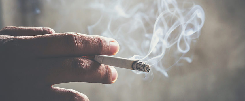 man holding smoking a cigarette in hand. Cigarette smoke spread.