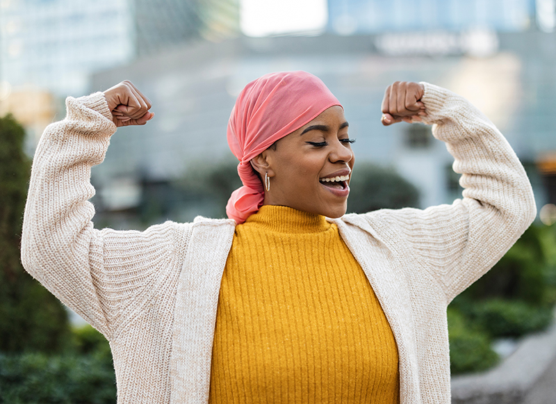 Latina woman, fighting breast cancer, wears a pink scarf, and cl